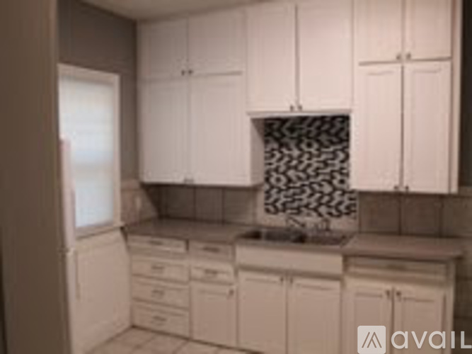 A kitchen with white cabinets and a black and white backsplash.