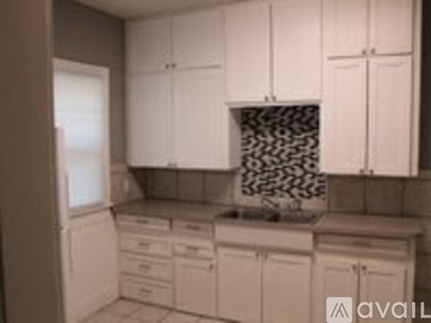 A kitchen with white cabinets and a black and white backsplash.