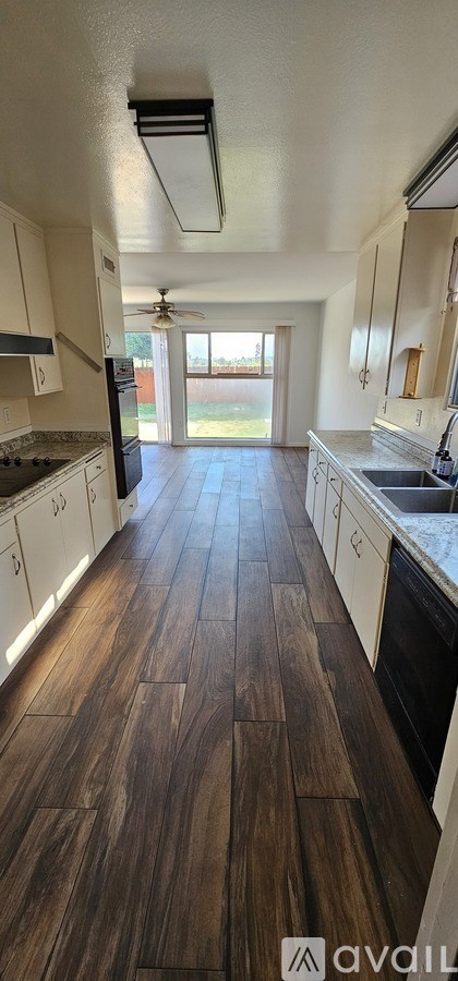 A kitchen with white cabinets and a wooden floor.