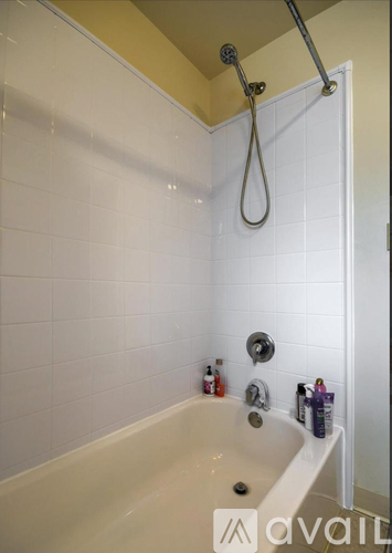 A white bathtub with a shower head and a shower curtain rod.
