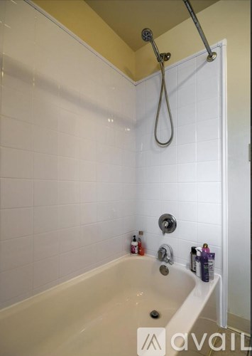 A white bathtub with a shower head and a shower curtain rod.