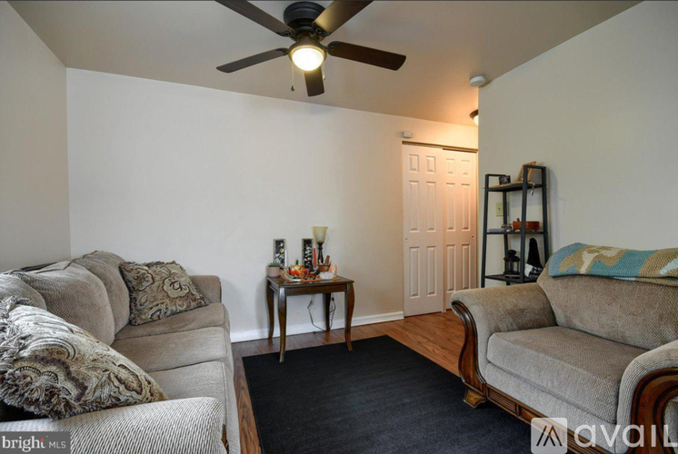 A living room with a couch, a chair, and a ceiling fan.
