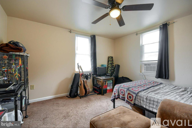 A bedroom with a bed, guitar, chair, and a bird cage.
