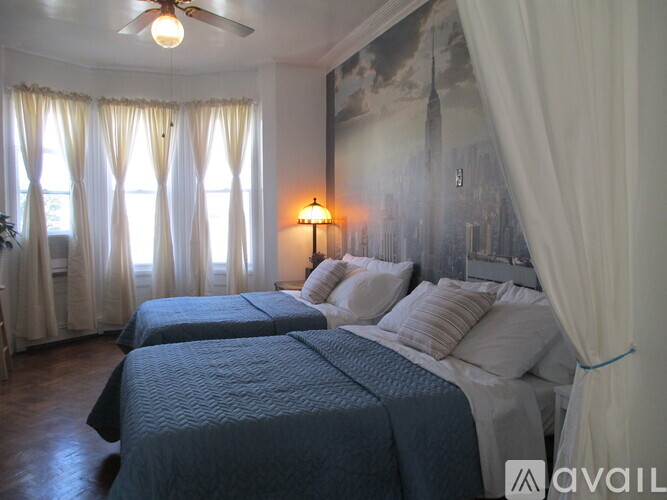 A bedroom with two beds and a large painting on the wall.