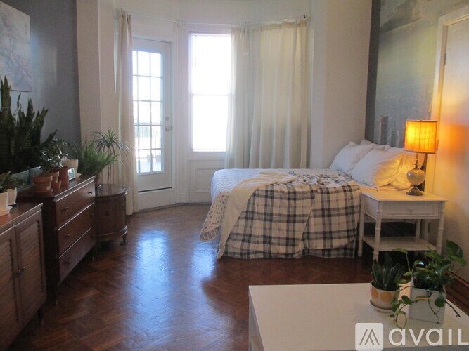 A bedroom with a bed, nightstand, and a window with curtains.