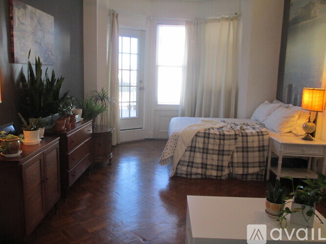 A bedroom with a bed, nightstand, and a window with curtains.