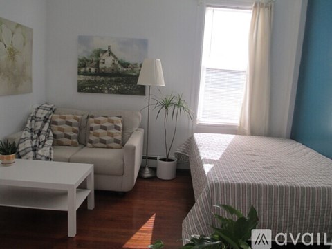 A living room with a couch, a bed, and a painting on the wall.