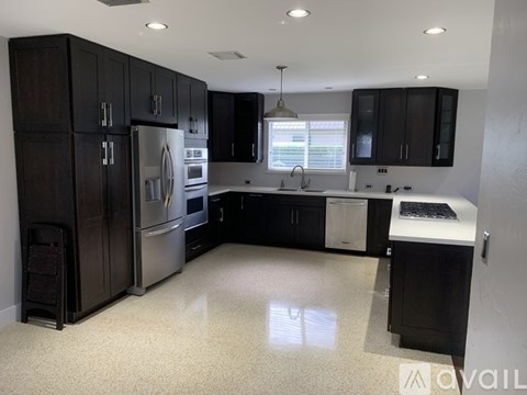 A kitchen with black cabinets and stainless steel appliances.