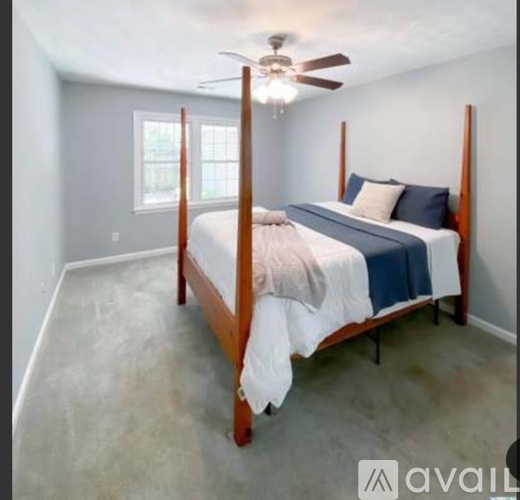 A bedroom with a four-poster bed and a ceiling fan.