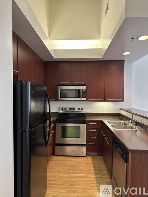 A kitchen with a black refrigerator and wooden cabinets.