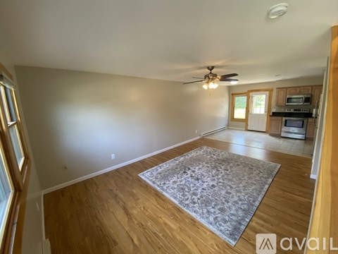 A living room with a ceiling fan and a rug on the floor.