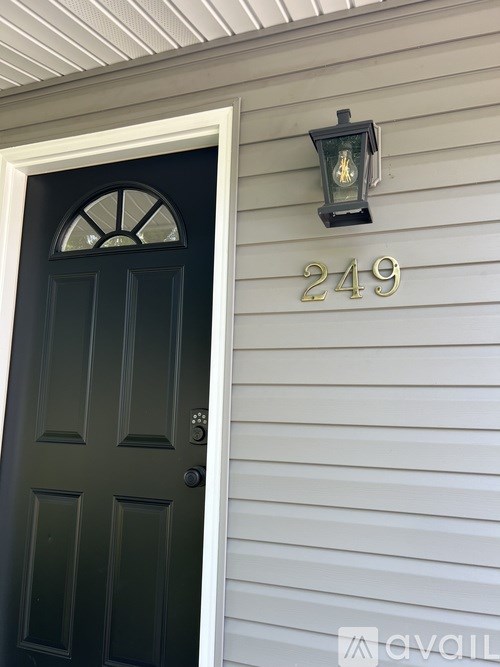 A black door with a window above it and a light on the wall above the door.