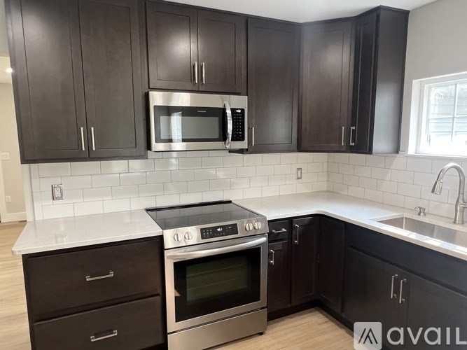 A kitchen with dark brown cabinets and stainless steel appliances.