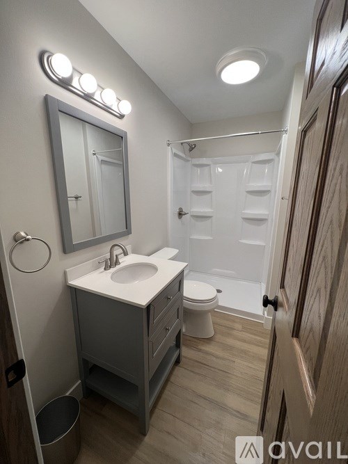 A bathroom with a sink, mirror, toilet and lights.