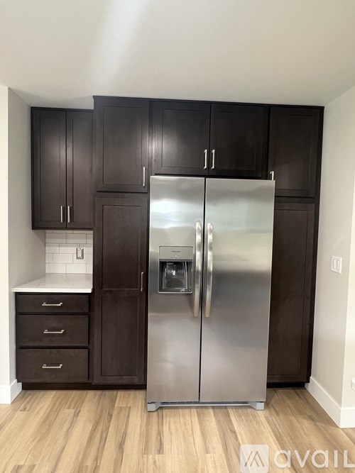 A kitchen with a stainless steel refrigerator and wooden cabinets.