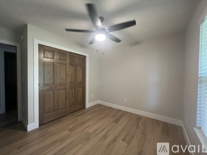 A room with a ceiling fan and a wooden door.
