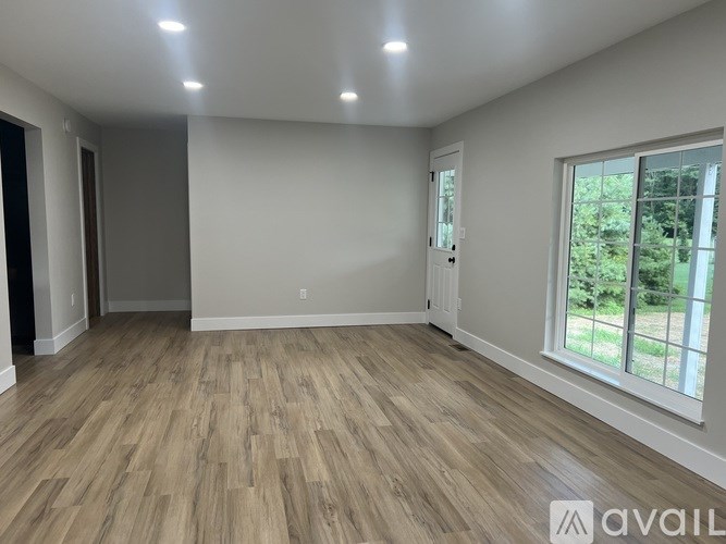A spacious room with wooden flooring and a large window.