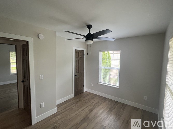 A room with a ceiling fan and a window with blinds.