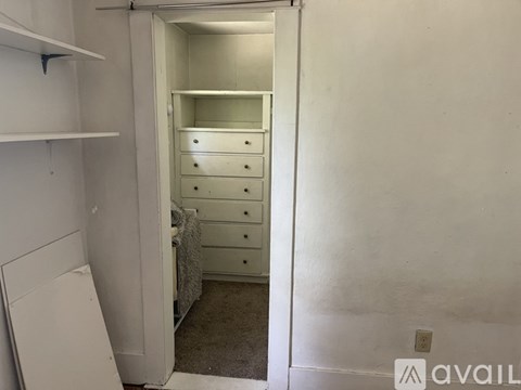 A white bedroom with a bed and a dresser in it.