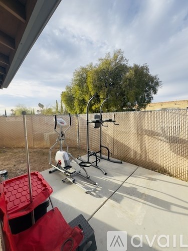 A red chair is placed on a patio with a white table and a red container.