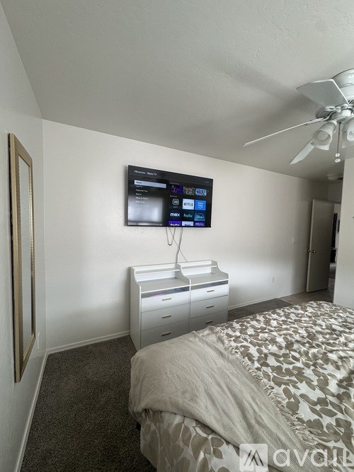 A bedroom with a bed, a television, and a ceiling fan.