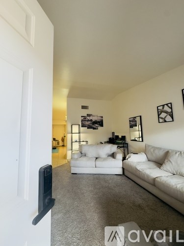 A living room with white furniture and pictures on the wall.