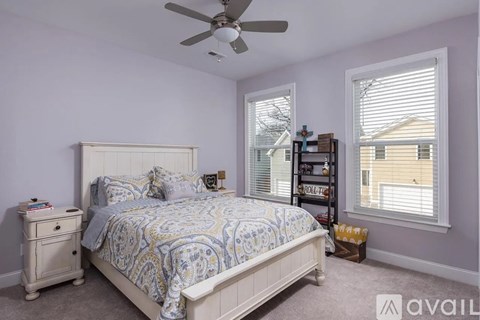 A bedroom with a bed, nightstand, and a fan.