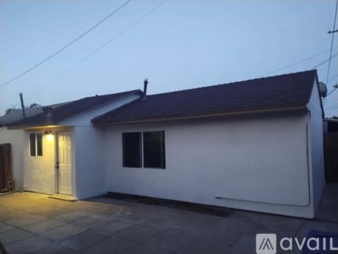 A small white house with a dark roof and a lit-up door.