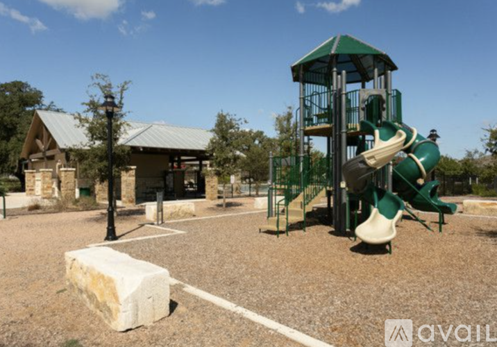 A playground with a green slide and a wooden structure in the background.