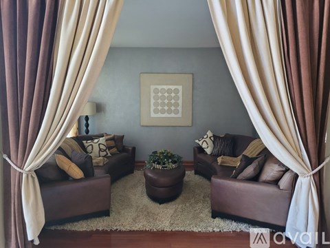 A living room with brown couches and a large painting on the wall.