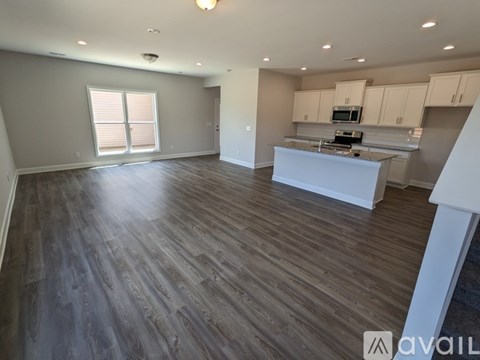 A spacious living room with a kitchen in the background.