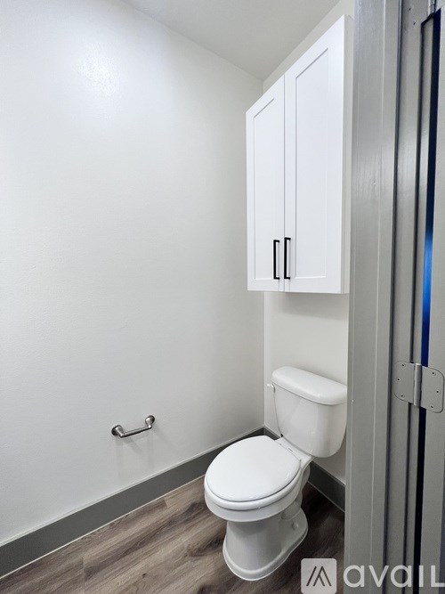 A white toilet in a small bathroom with a cabinet above it.