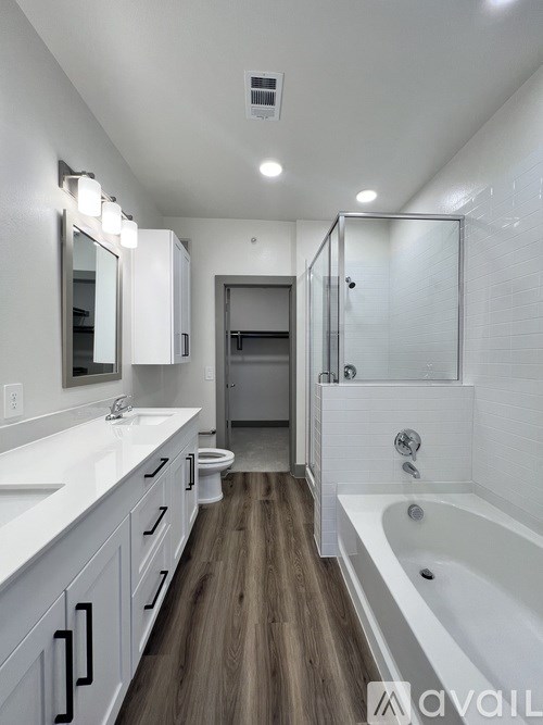 A modern bathroom with a white tub and wooden floors.