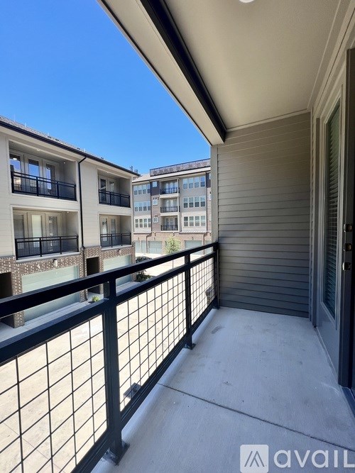 A balcony with a black railing and a view of other buildings.