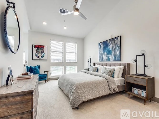 A living room with a grey couch and a large painting on the wall.