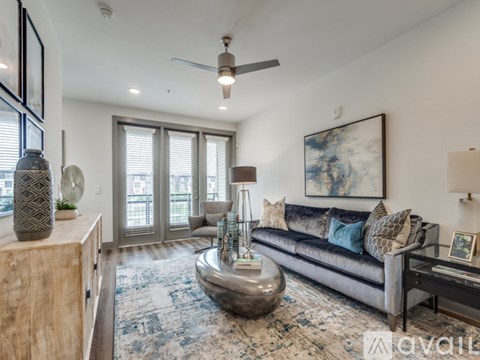 A living room with a grey couch and a large painting on the wall.