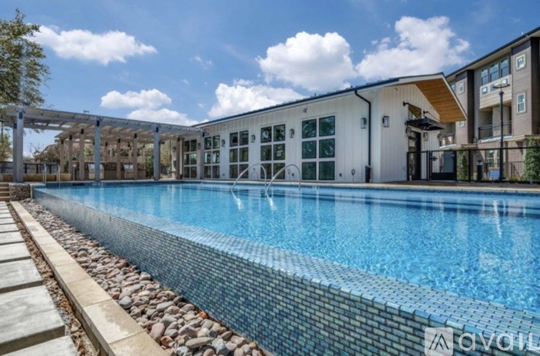 A swimming pool with a tiled edge and a building in the background.