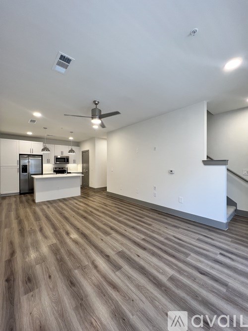 A spacious room with a ceiling fan and a staircase.