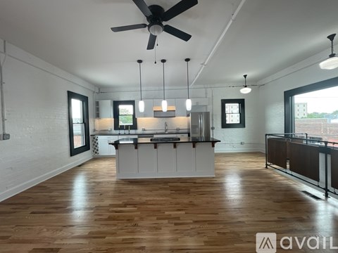 A spacious kitchen and living room with wooden floors and white walls.
