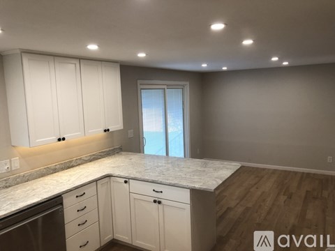 A kitchen with white cabinets and a marble countertop.