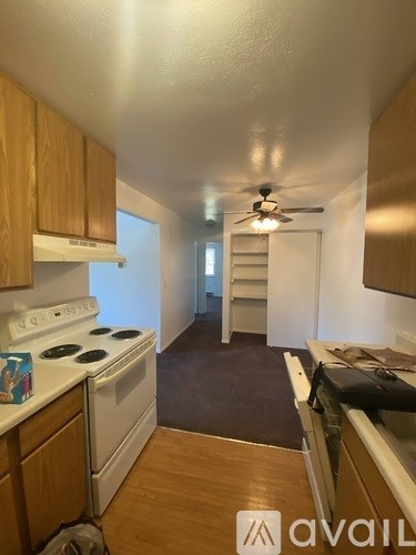 A kitchen with a stove top oven and wooden cabinets.
