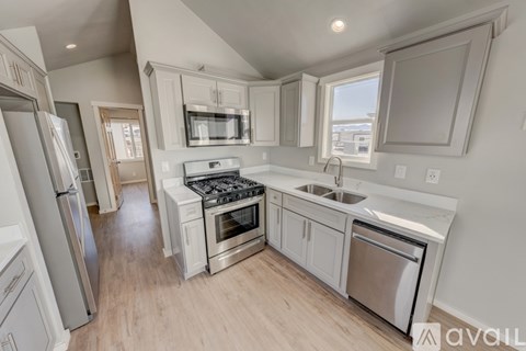 A kitchen with white cabinets and stainless steel appliances is available for rent.