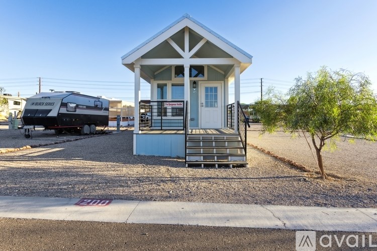 A small white house with a porch and a tree in front of it.