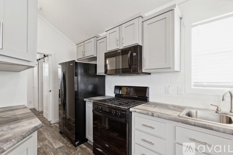 A kitchen with black appliances and white cabinets.