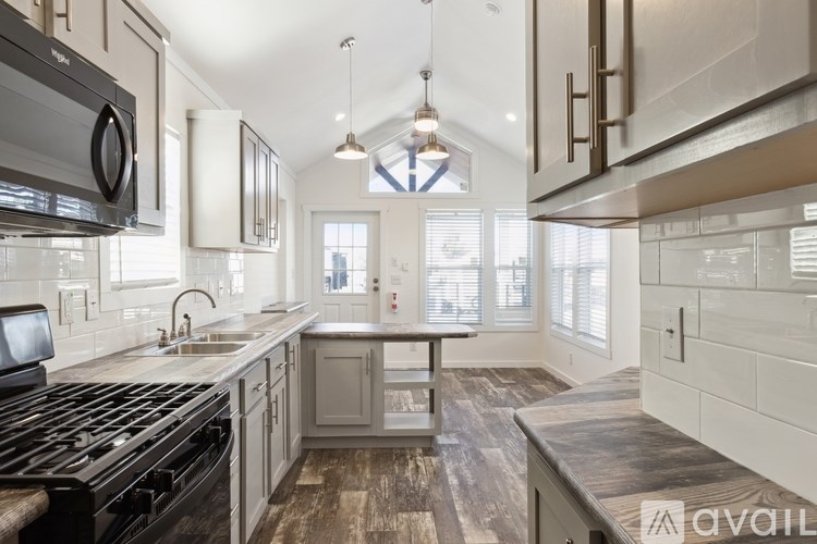 A modern kitchen with a black stove top oven and wooden flooring.