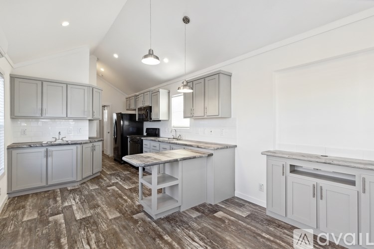 A kitchen with wooden floors and grey cabinets.