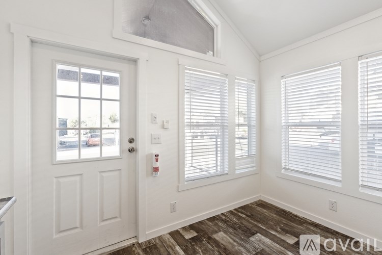 A room with a door, windows with blinds, and a fire extinguisher on the wall.