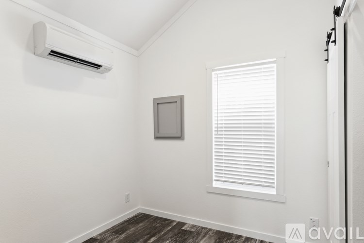 A room with a window, a picture frame, and a wall-mounted air conditioner.