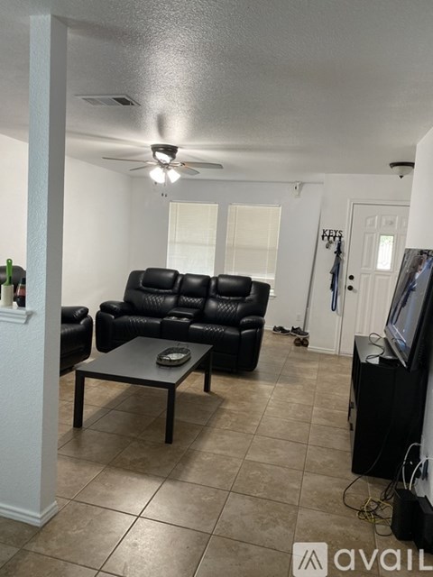 A living room with a black leather couch and a television.