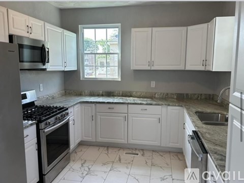 A kitchen with white cabinets and a marble countertop.